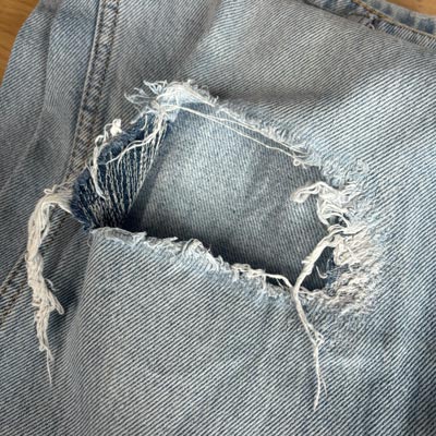 Réparer un trou en couture sur le genou d'un pantalon en jeans